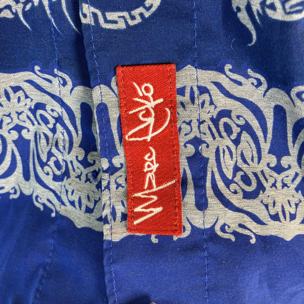 Close-up of a royal blue patterned garment with a red fabric brand tag featuring white embroidered script.