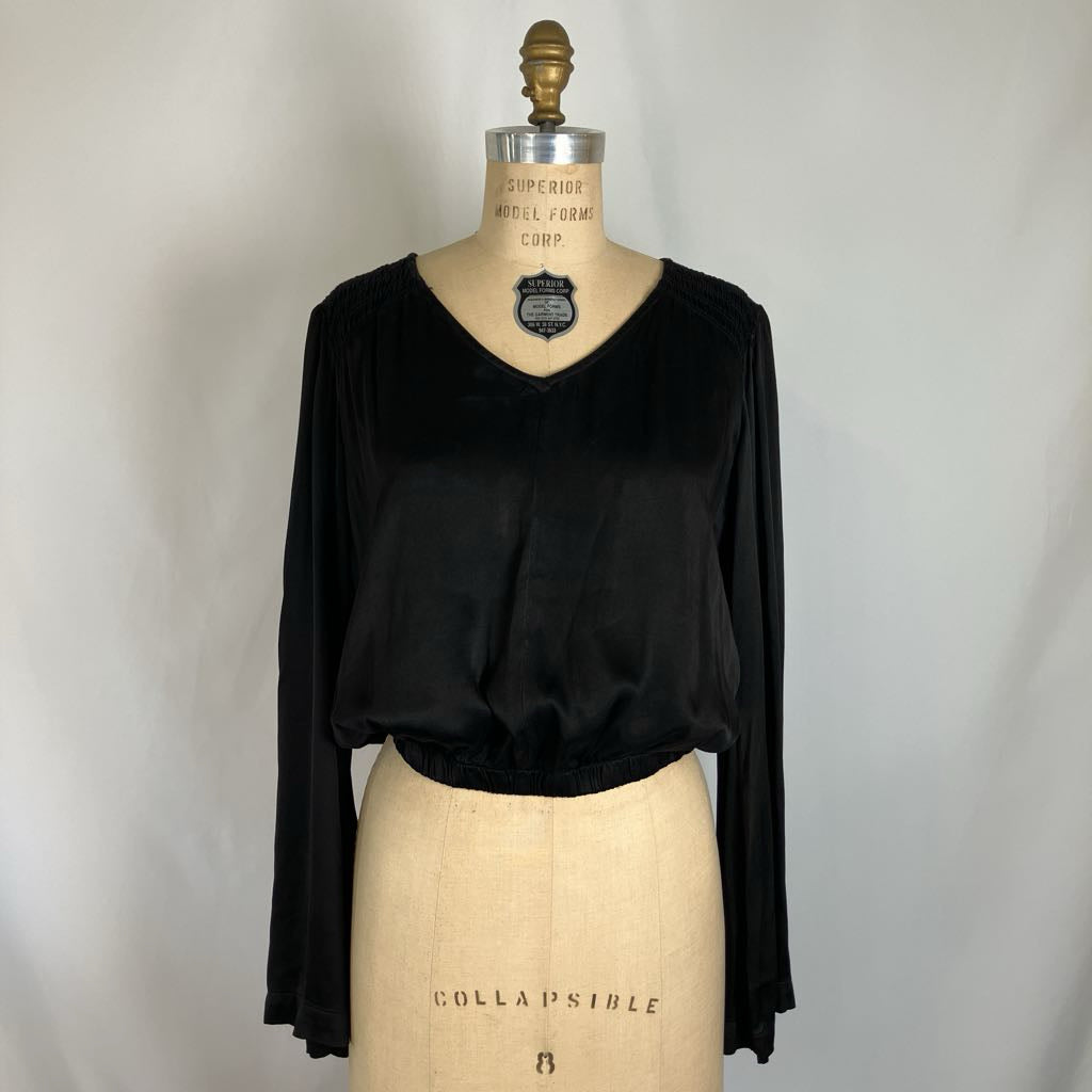 A black long-sleeve V-neck blouse displayed on a beige dress form mannequin against a light gray fabric backdrop.