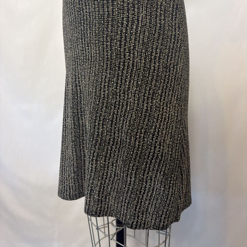 A black and white textured tweed skirt displayed on a wire dress form against a white fabric backdrop.