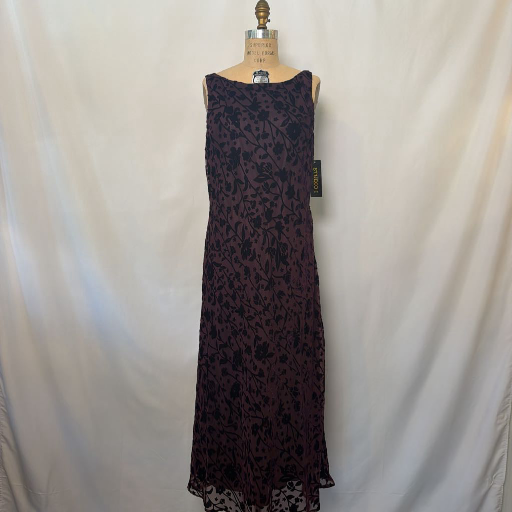 A sleeveless dark plum lace maxi dress displayed on a dress form mannequin against a draped white fabric backdrop.