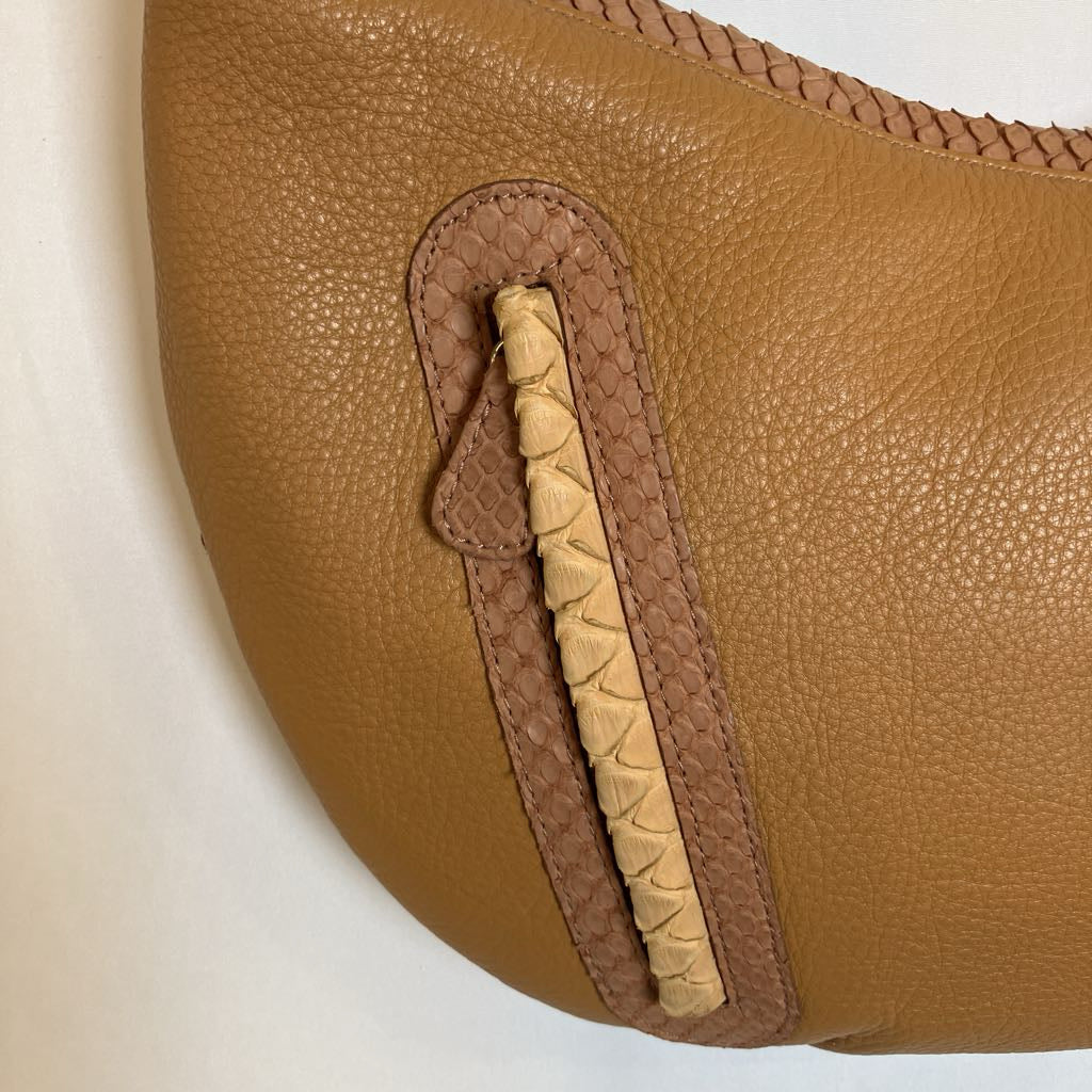 Close-up of a tan pebbled leather bag with a vertical braided tan and beige leather accent panel.