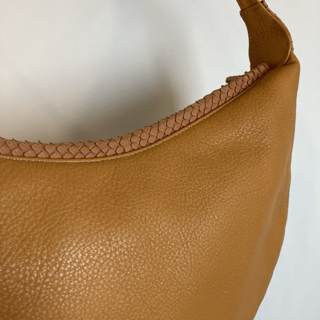 A close-up of a tan pebbled leather hobo bag with a woven leather trim along the curved top edge, shown against a plain light background.