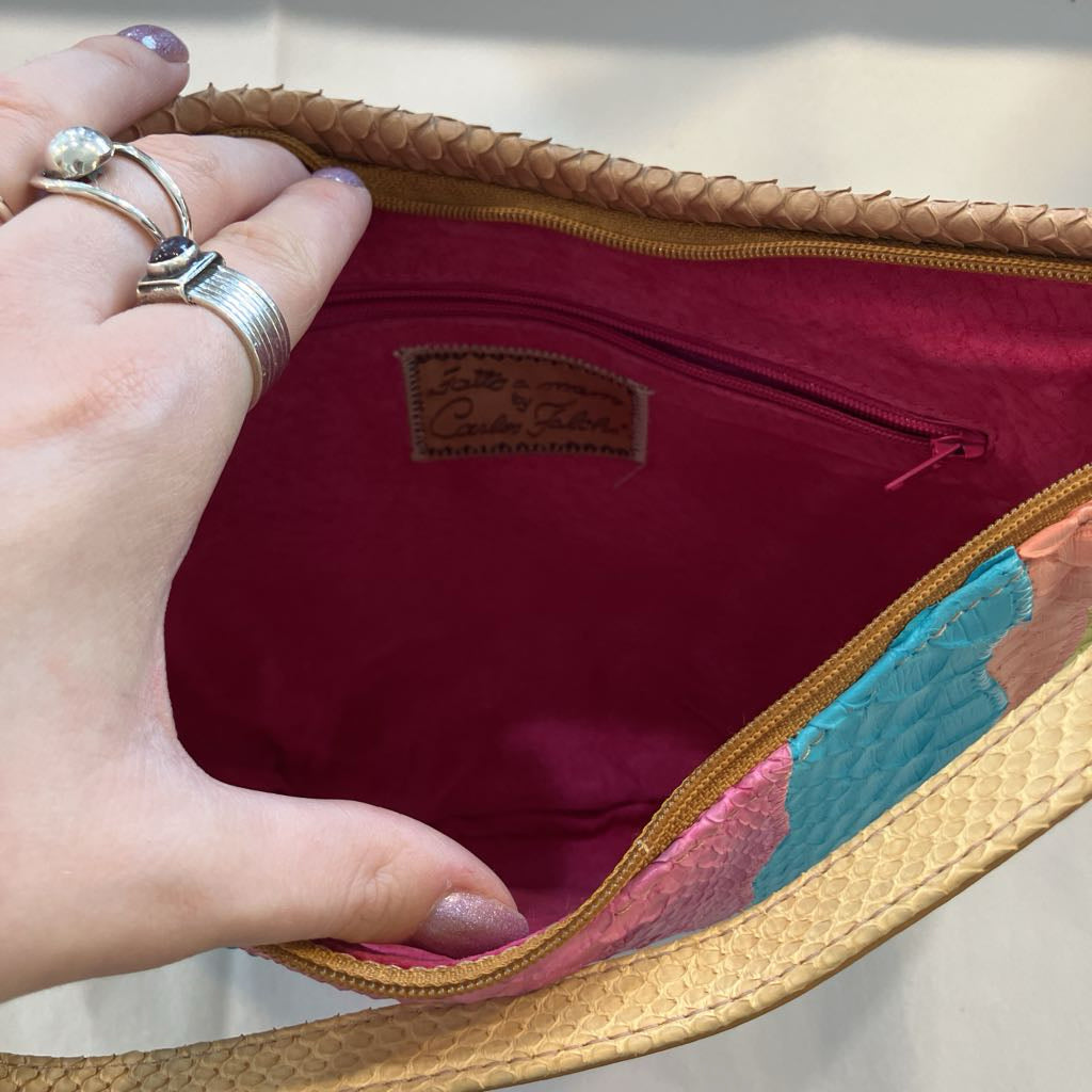 A close-up of a hand holding open a woven tan shoulder bag to show the interior. The inside lining is a deep magenta pink with a zippered pocket and a small brand patch that reads 'Lotto & Co.