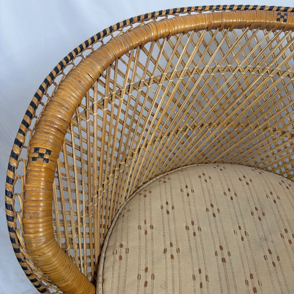 Close-up of a woven rattan chair back and seat cushion, showing natural tan wicker with black decorative accents and a beige patterned fabric seat.