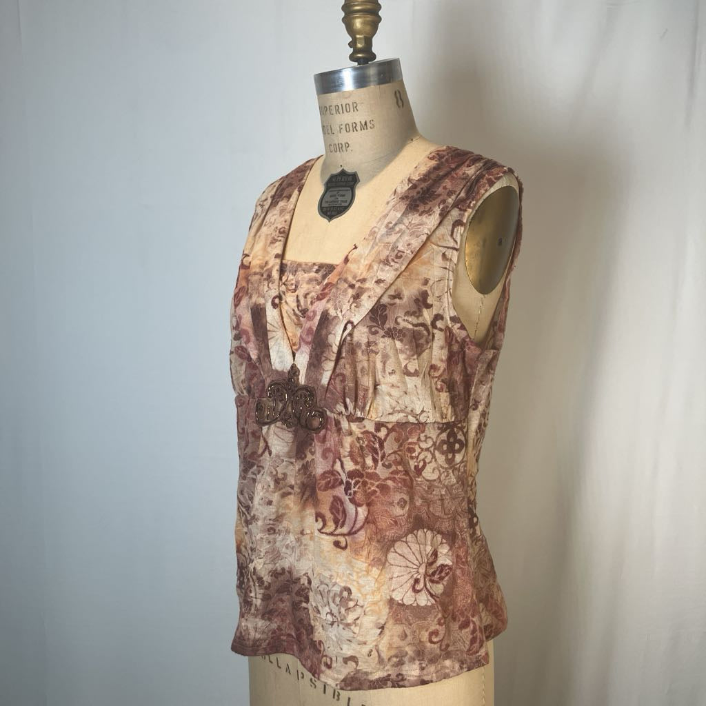 A sleeveless V-neck blouse with a brown and beige floral/ornamental print, displayed on a vintage dress form mannequin against a light gray fabric backdrop.