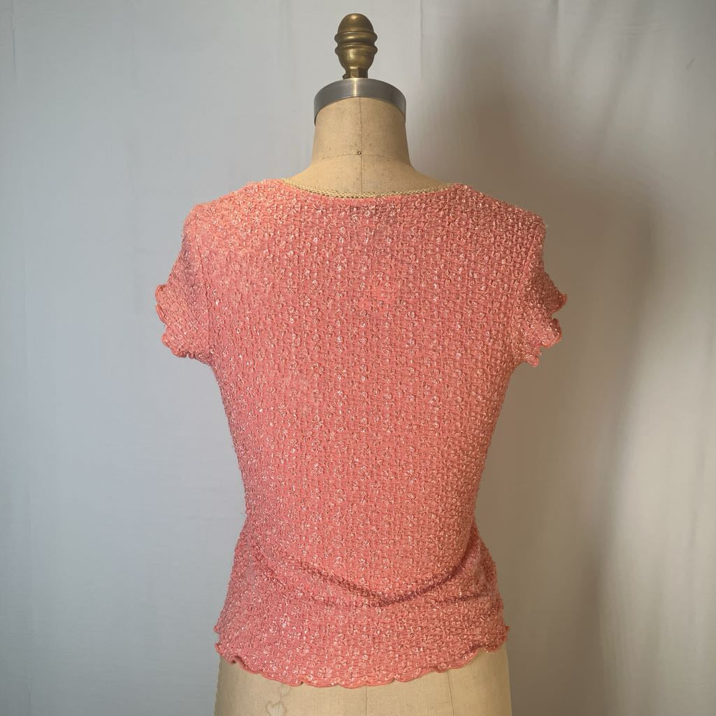 A coral pink textured short-sleeve top displayed on a dress form mannequin against a plain light gray background.
