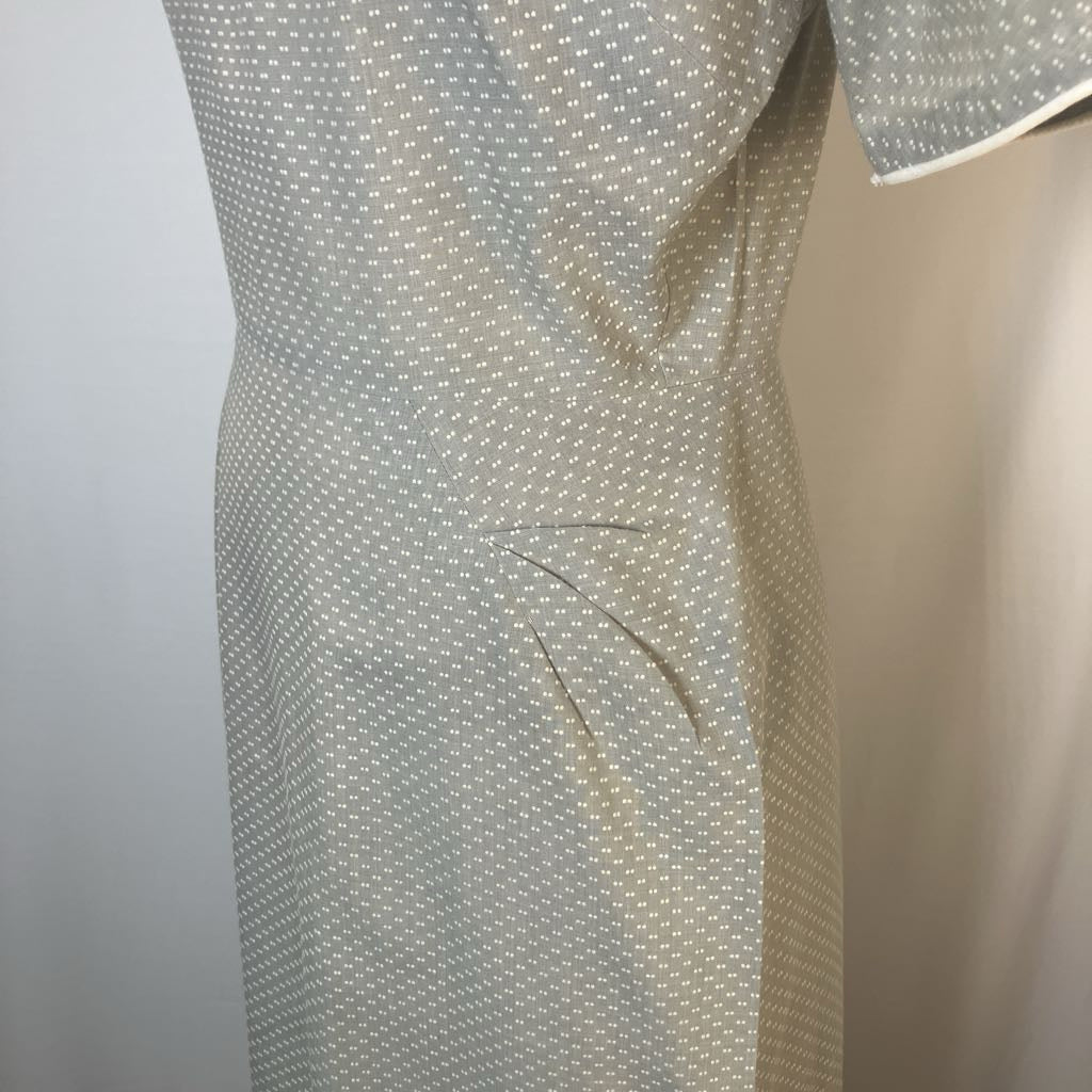 A close-up of a light gray and white micro-patterned dress or skirt, showing the fabric texture and a side seam.