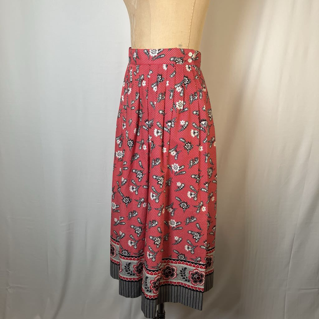 A red midi skirt with a black and white floral print, displayed on a beige dress form against a light gray fabric backdrop.