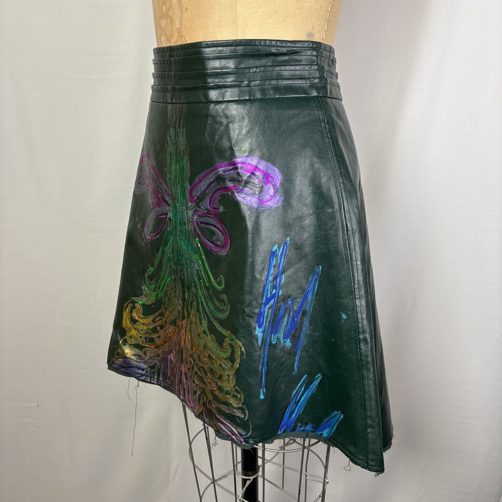 A dark green faux-leather A-line skirt with colorful chalk-style abstract drawings, displayed on a dress form mannequin against a white fabric backdrop.