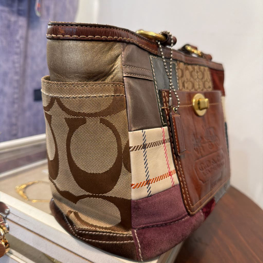 A Coach patchwork shoulder bag featuring multiple panels of brown leather, the signature monogram canvas, a plaid pattern, and a burgundy suede section, resting on a display stand.
