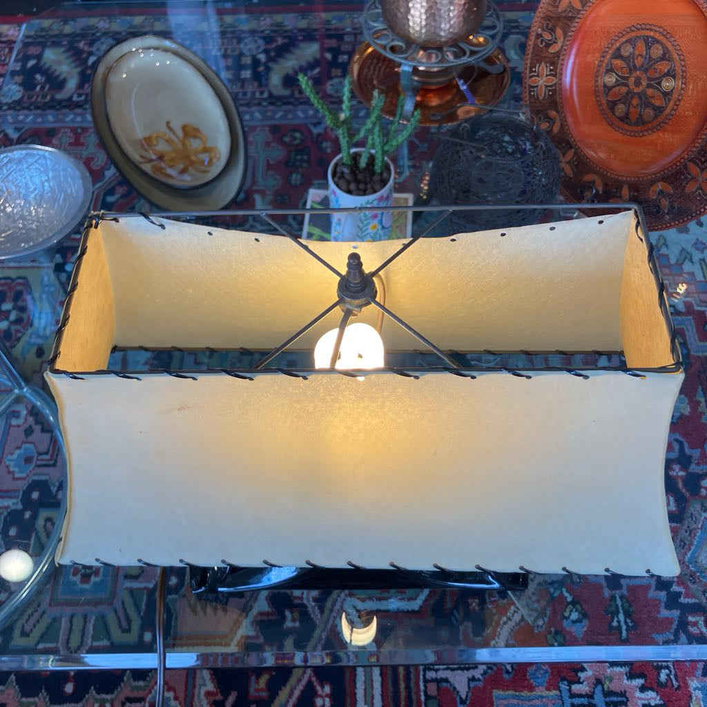 Mid-century lamp with a large trapezoidal shade in a store setting.