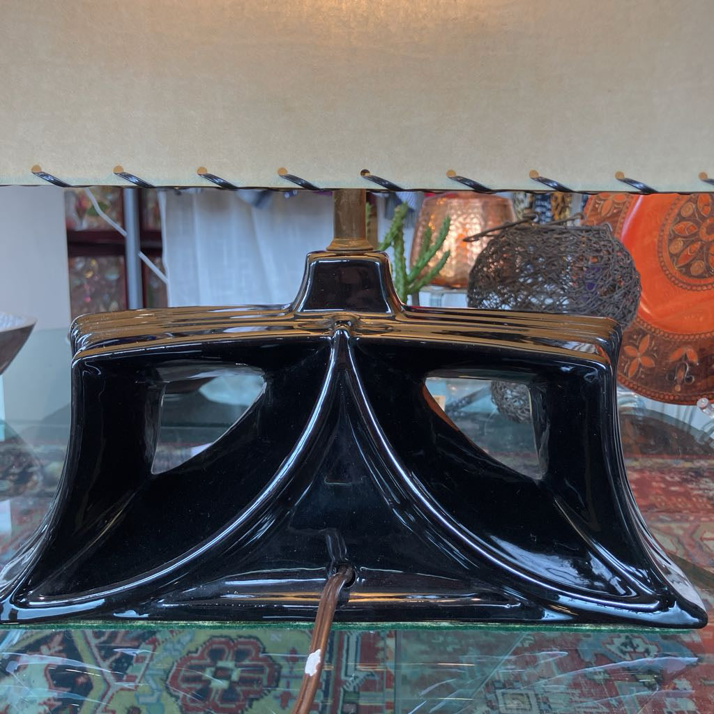 Mid-century lamp with a black ceramic angular base and a shade in a store setting.