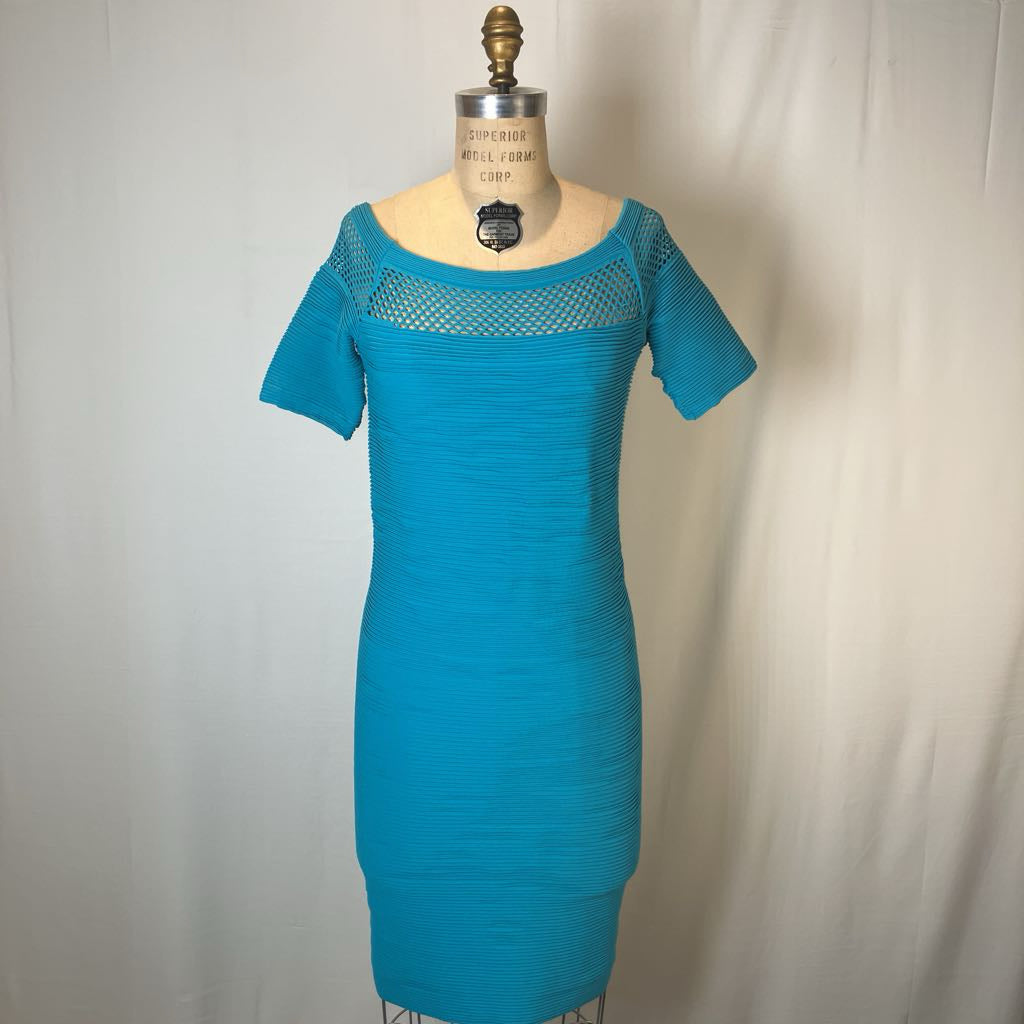 A bright turquoise blue short-sleeve knit dress displayed on a vintage dress form mannequin against a white fabric backdrop.
