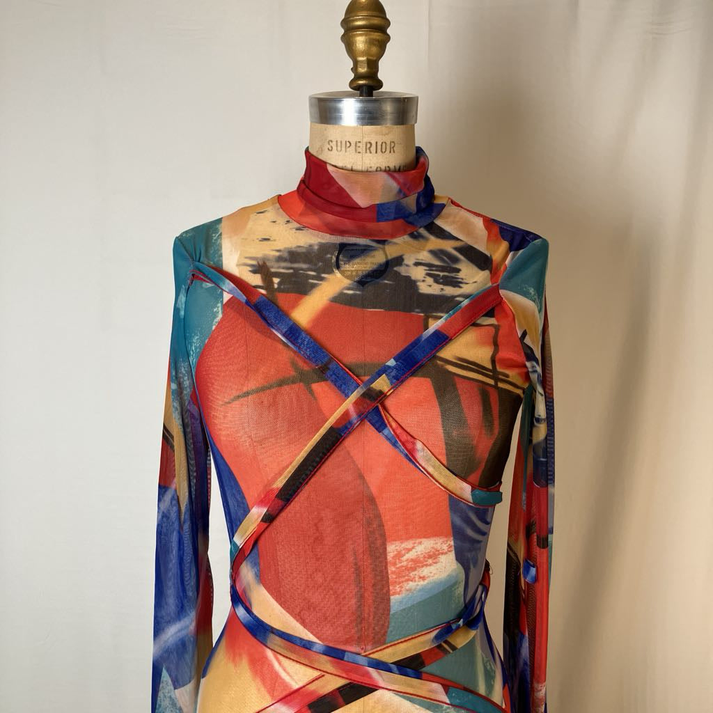 A long-sleeve mock-neck wrap dress with an abstract multicolor print, displayed on a vintage mannequin dress form against a neutral off-white background.