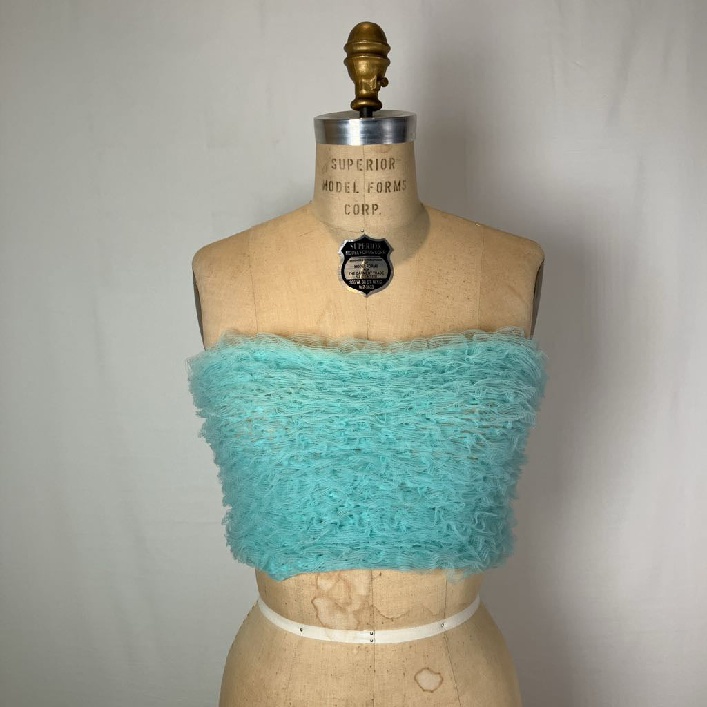 A turquoise fuzzy knit strapless bandeau top displayed on a vintage tan mannequin torso against a light gray fabric backdrop.