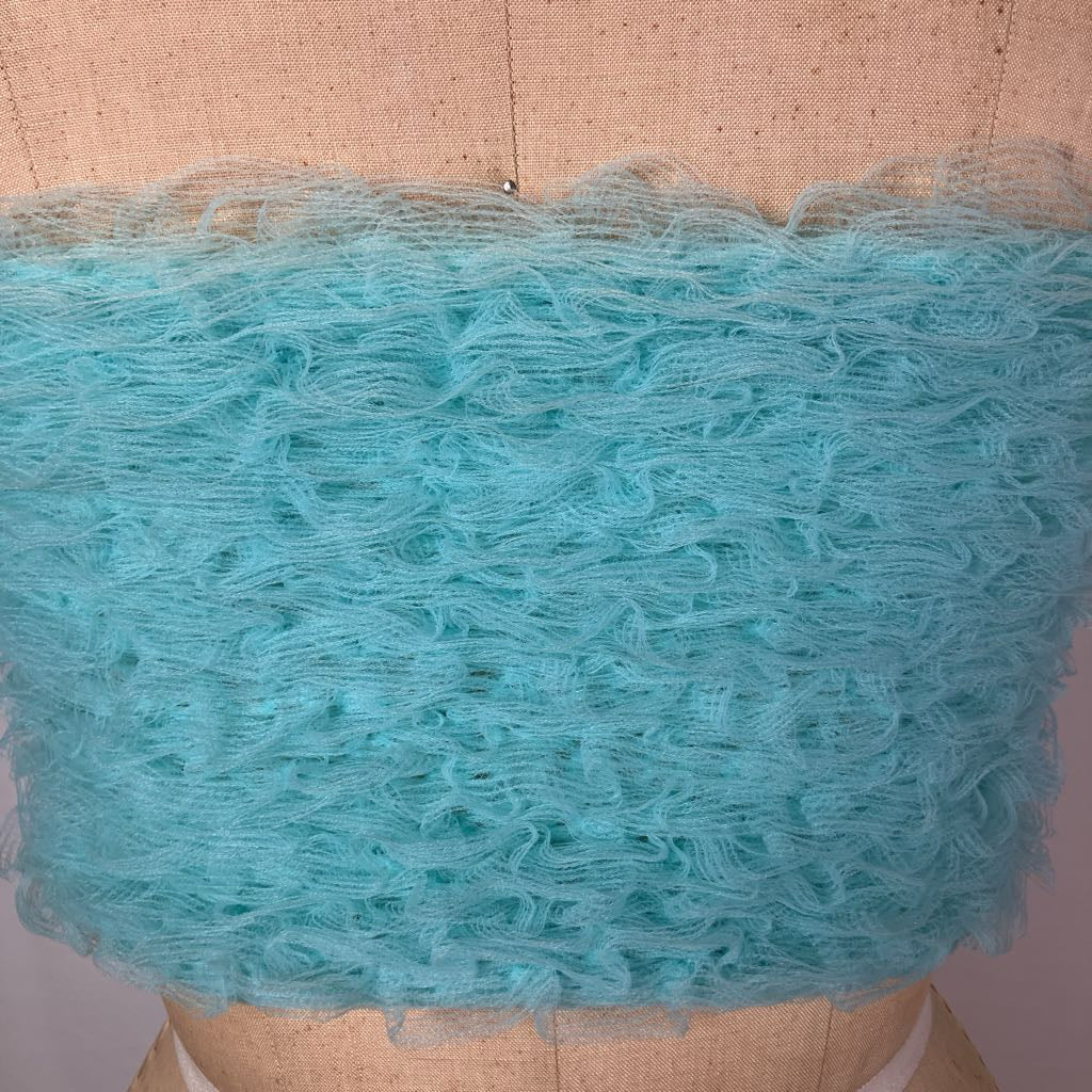 A close-up of a light aqua blue sheer mesh fabric with a ruffled, textured edge, displayed on a beige fabric mannequin torso.