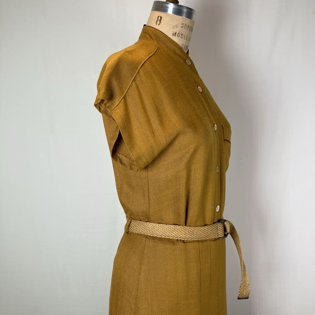 A mustard yellow linen shirt dress displayed on a vintage dress form mannequin against a plain off-white background.