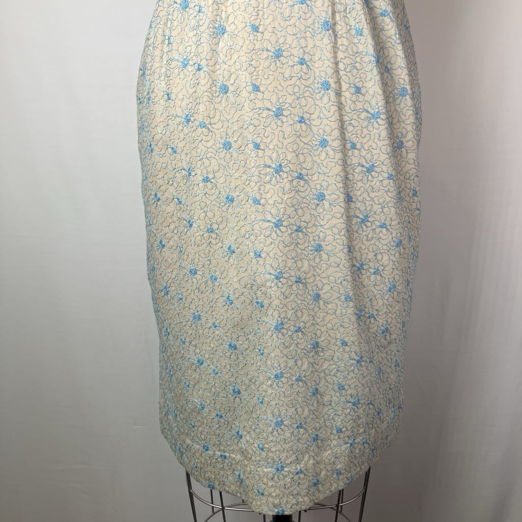 A cream-colored skirt with a light blue floral and swirl pattern, displayed on a dress form mannequin against a plain white background.