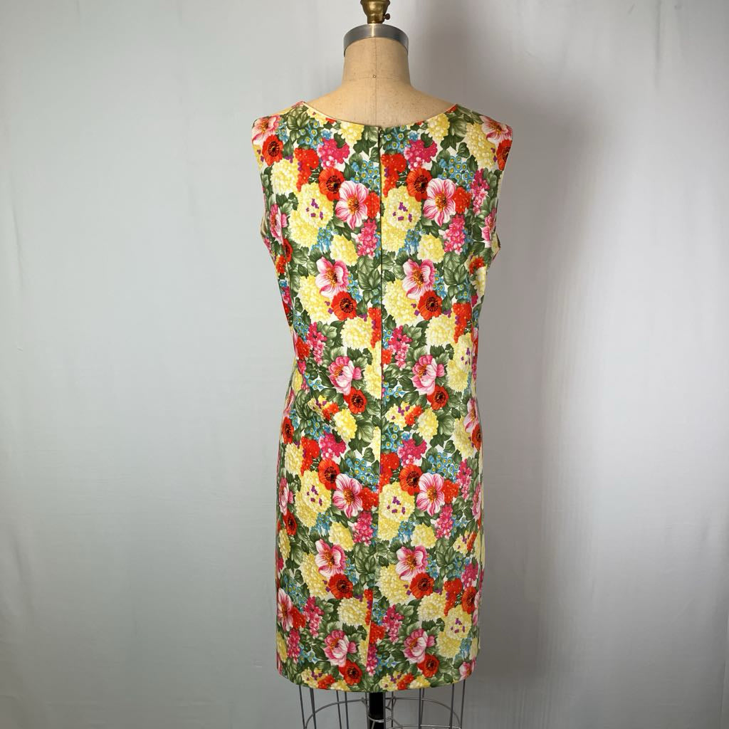A sleeveless sheath dress with a vibrant multicolor floral print, displayed on a dress form mannequin against a plain light gray background.
