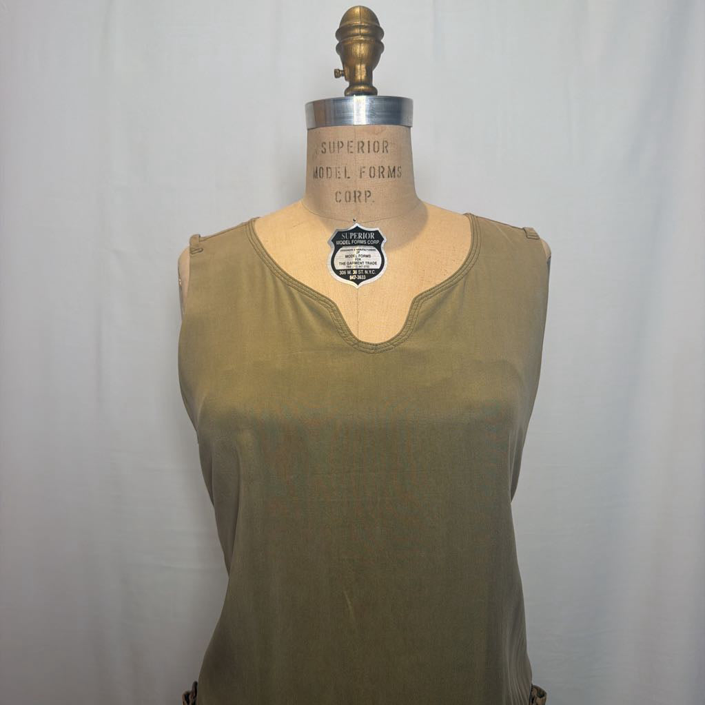 An olive green sleeveless top displayed on a vintage wooden dress form mannequin against a white fabric backdrop.