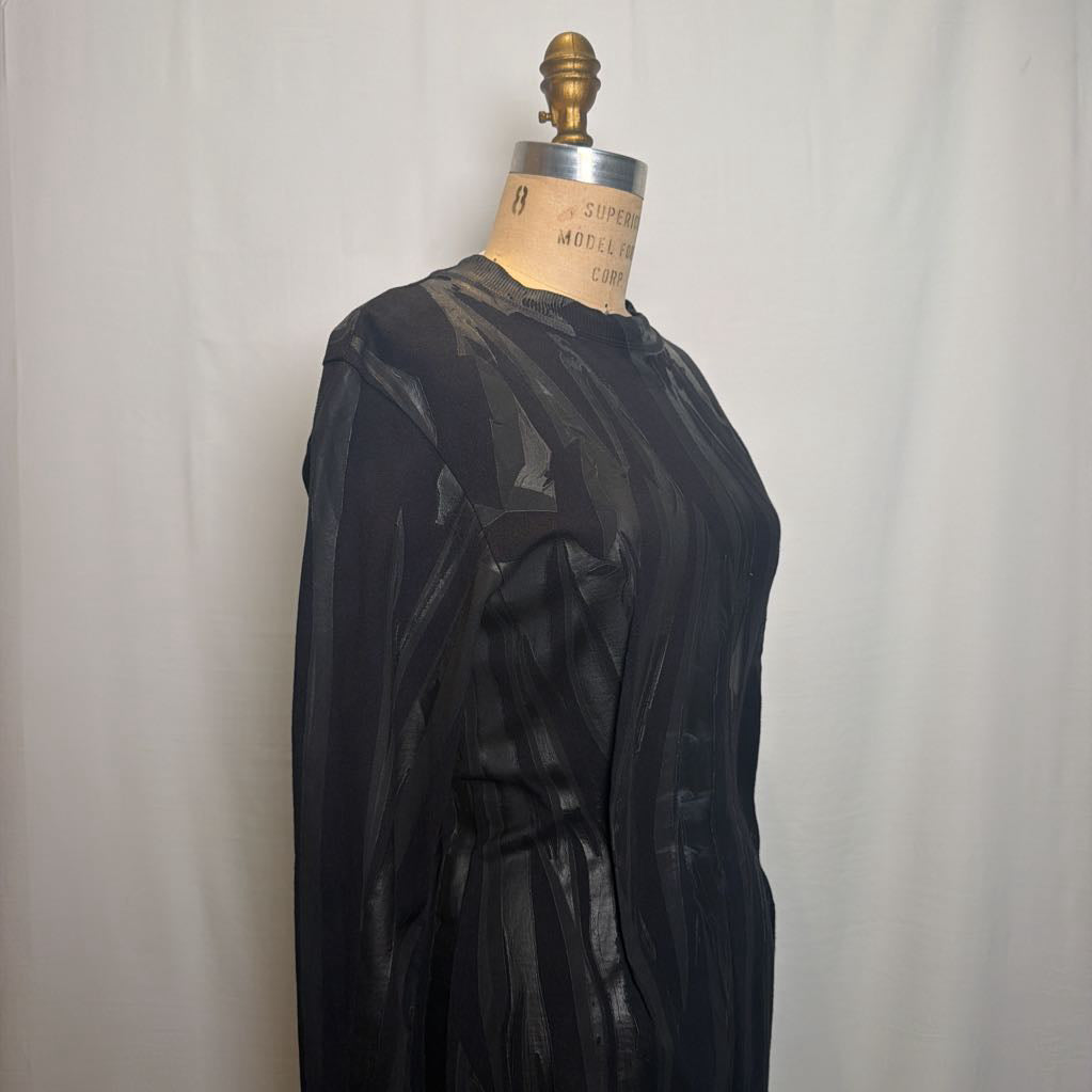 A black sheer long-sleeve top with a subtle tonal abstract pattern, displayed on a vintage dress form mannequin against a white fabric backdrop.