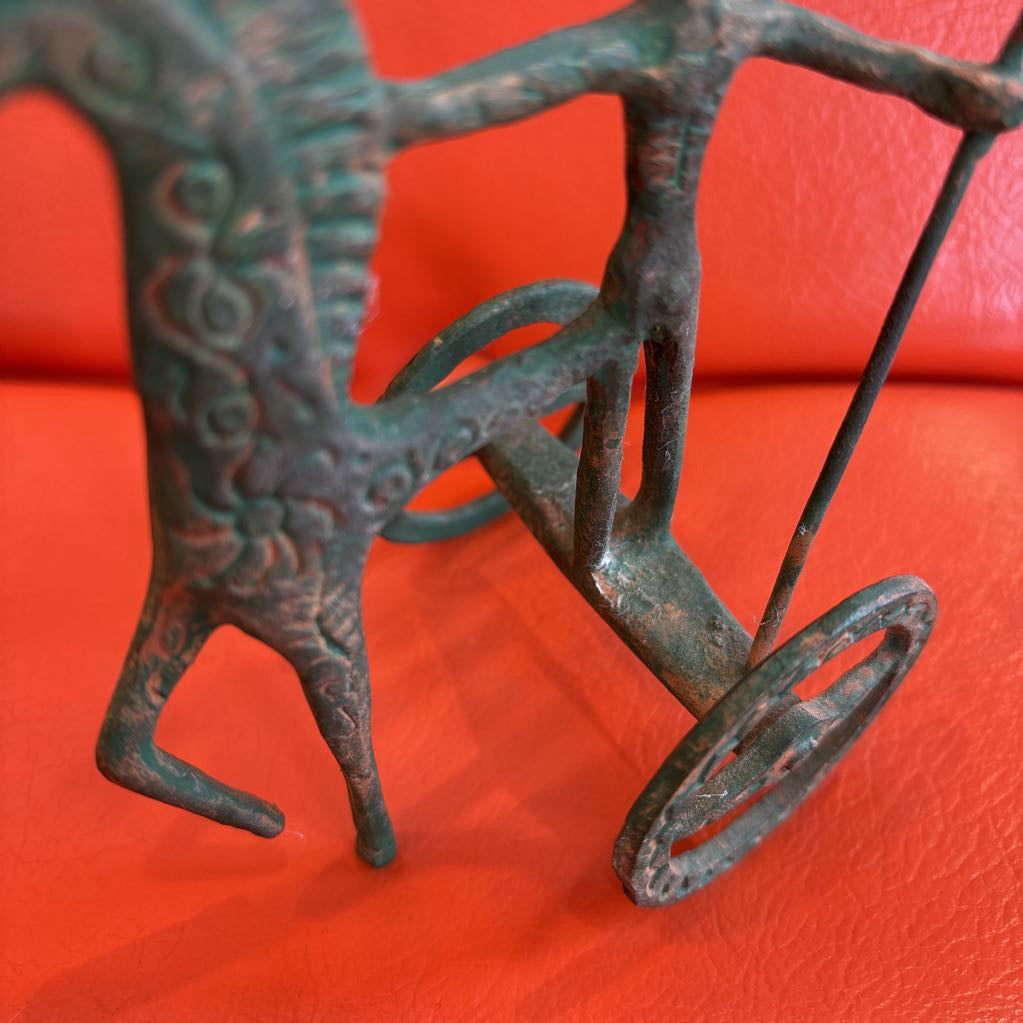 A metal ancient Greek style figure on an orange leather surface.