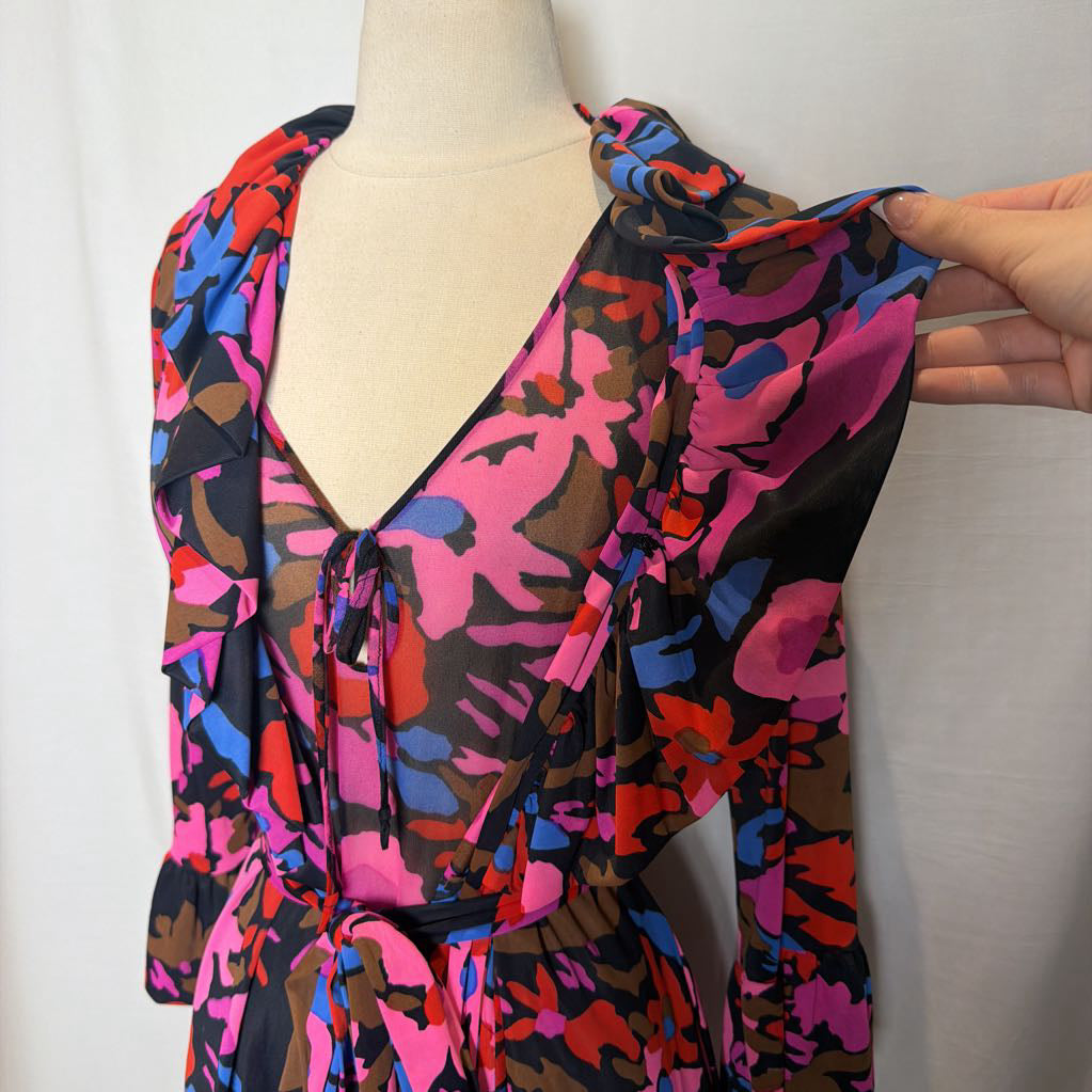 A multicolor abstract print wrap top on a cream dress form, with a hand holding up the sleeve to show the fabric drape.