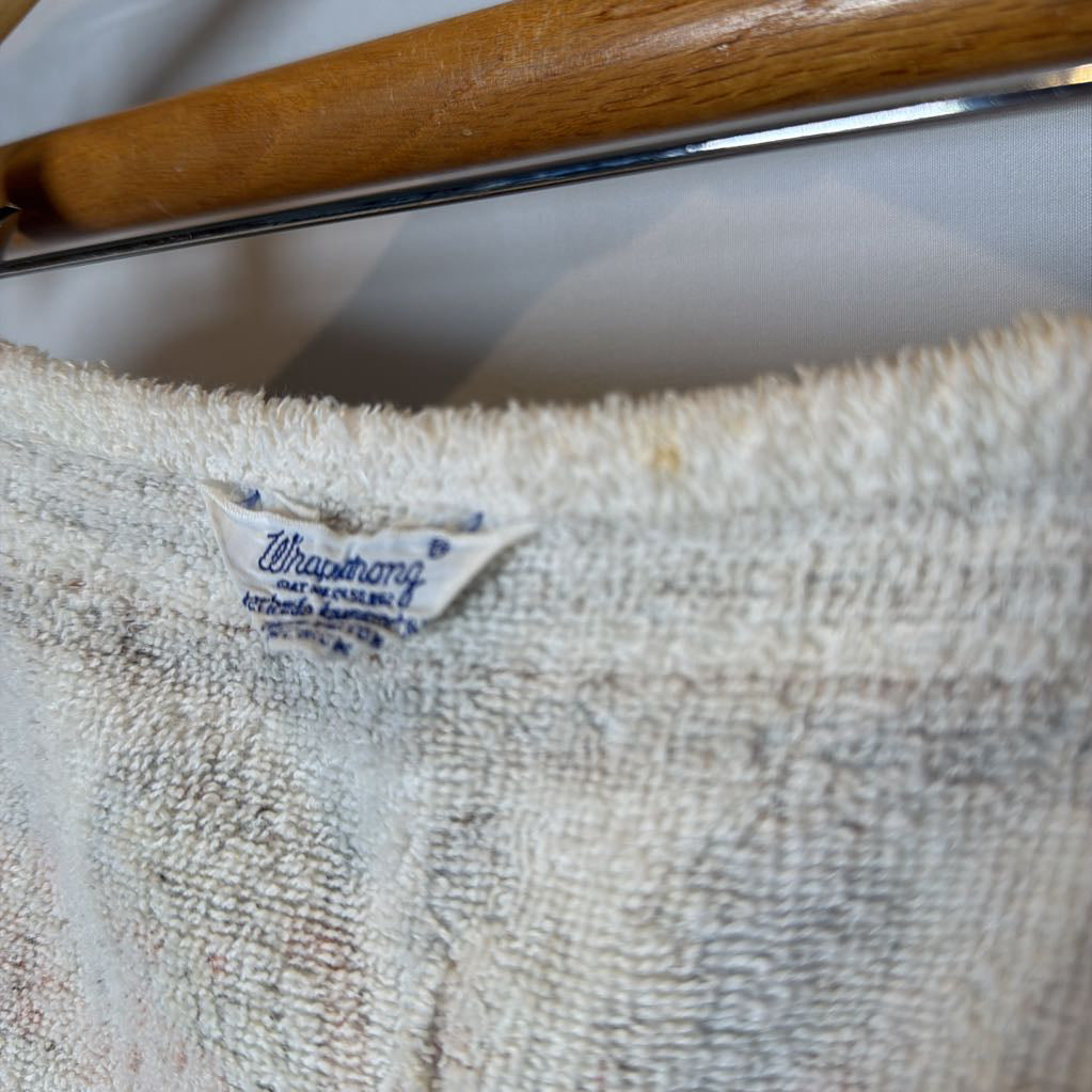Close-up of a textured cream-colored terry cloth garment hanging on a wooden hanger, showing a visible Whiskerman brand label.