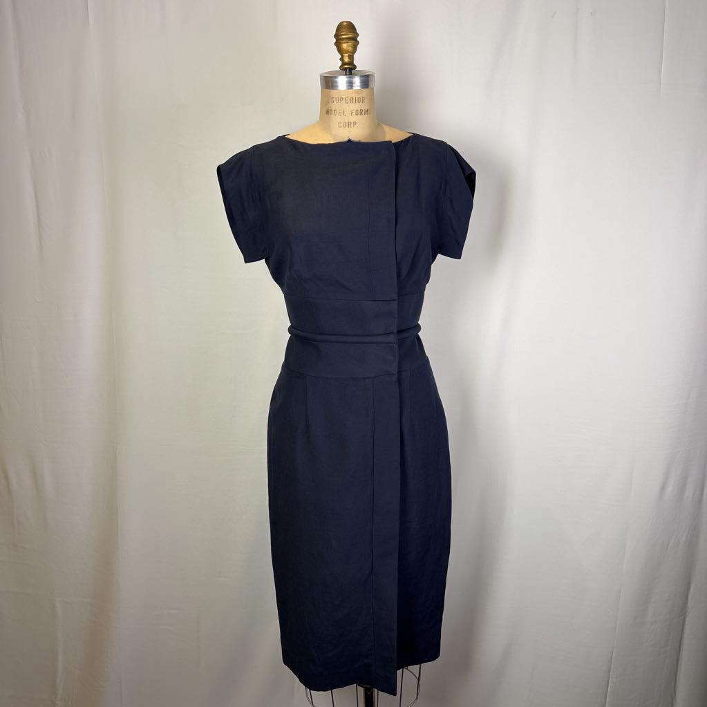 A dark navy blue knee-length dress displayed on a dress form mannequin against a white fabric backdrop.