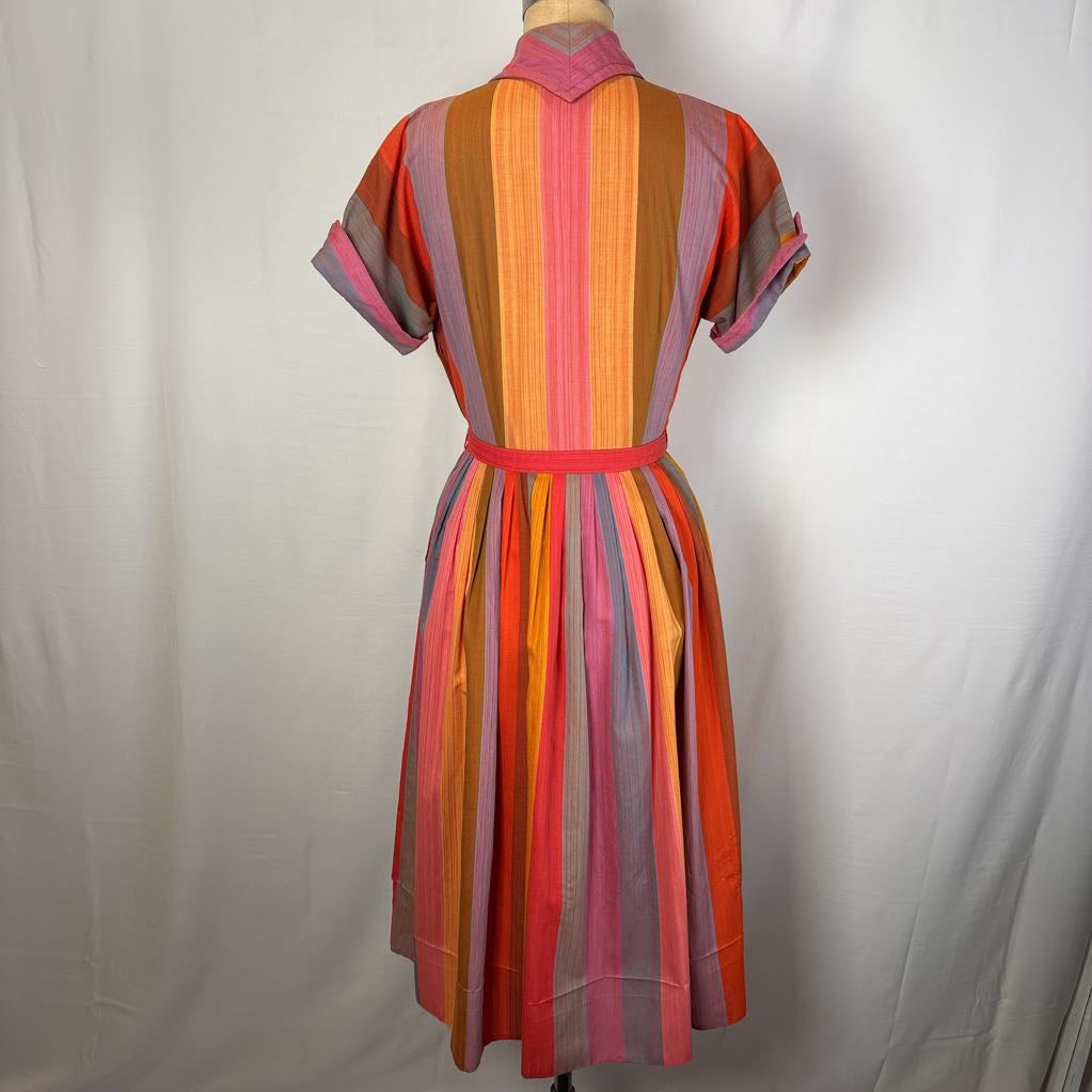 A short-sleeve collared dress with vertical multicolor stripes in pink, orange, yellow, purple, and gray, displayed on a dress form against a white fabric backdrop.