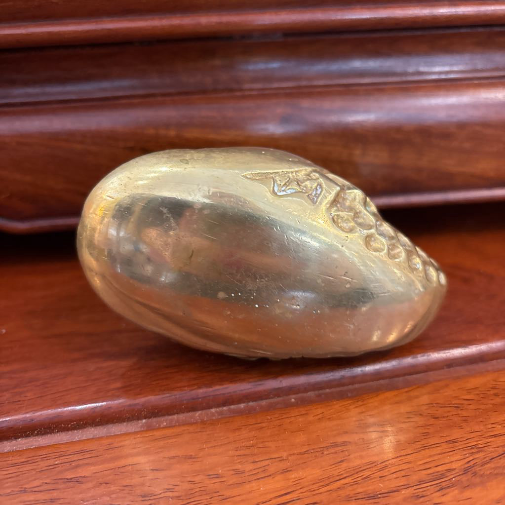 The bottom of a brass figure on a wooden surface.