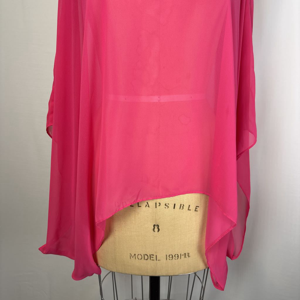 A bright pink sheer chiffon top draped over a beige dress form, photographed against a plain light gray wall.