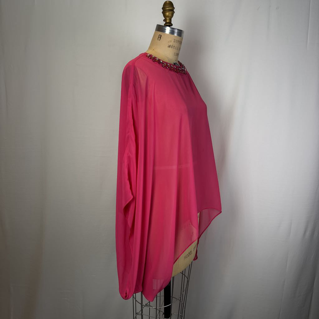 A bright pink sheer long-sleeve blouse with a beaded neckline, displayed on a vintage dress form mannequin against a white fabric backdrop.