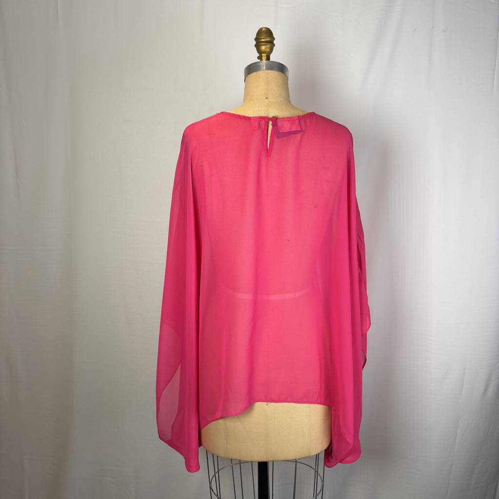 A bright pink sheer long-sleeve blouse displayed on a beige dress form against a white fabric backdrop.