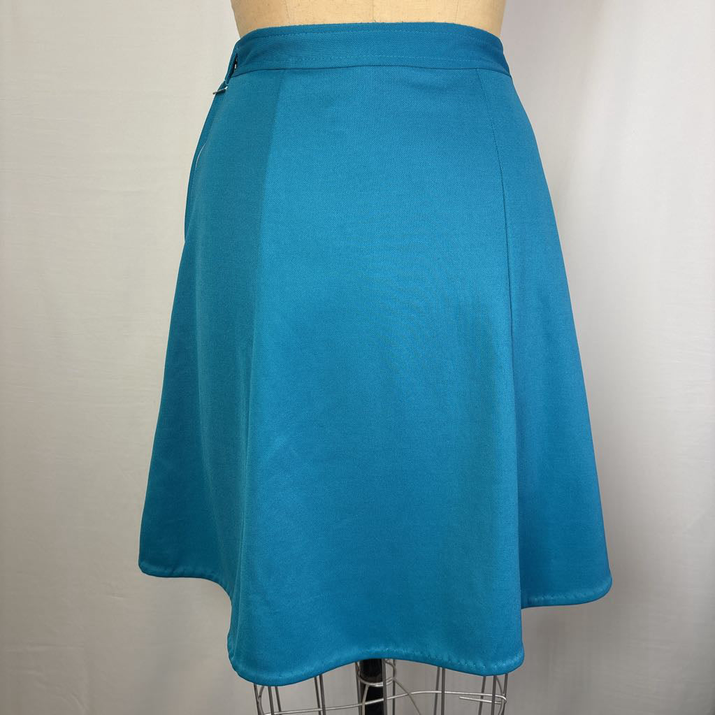 A teal blue A-line skirt displayed on a dress form mannequin against a light gray fabric backdrop.