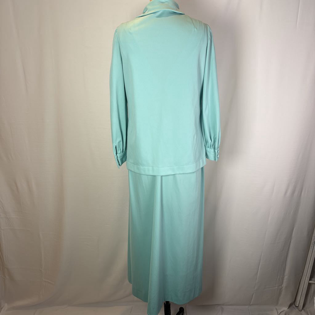 A mint green two-piece clothing set consisting of a long-sleeve collared top and a matching midi skirt, displayed on a mannequin against a white fabric backdrop.
