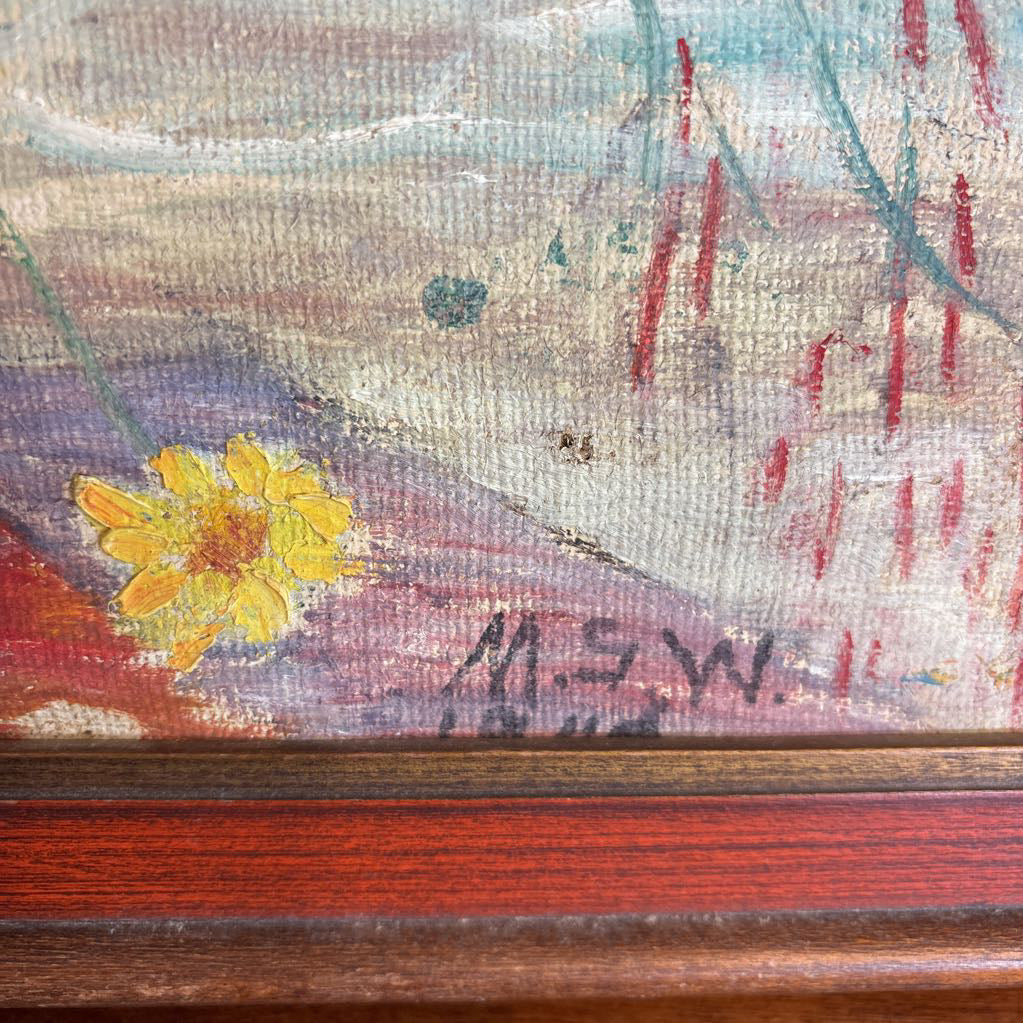 A framed still life of flowers in a vase on a wooden surface.