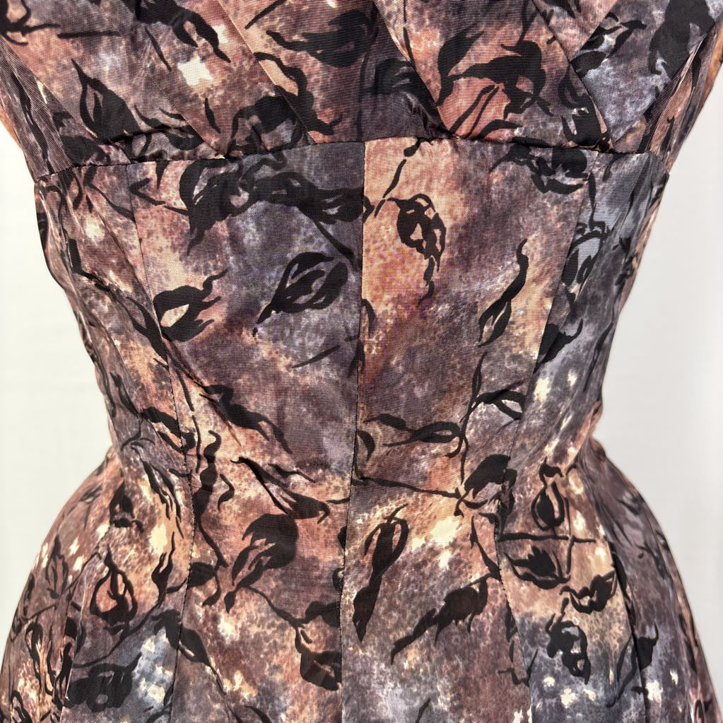 A vintage fit and flare A-line dress with an abstract pattern on a mannequin against a white wall.