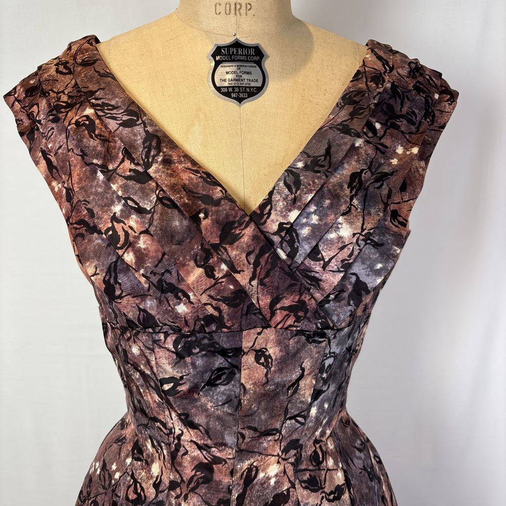 A vintage fit and flare A-line dress with an abstract pattern on a mannequin against a white wall.