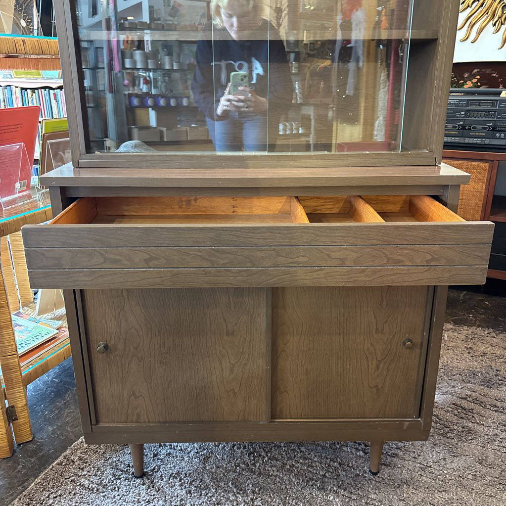 A large wooden hutch with two sliding wooden doors. The cabinet is in a store setting.