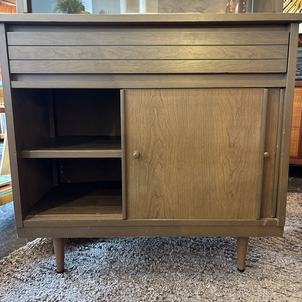 A large wooden hutch with two sliding wooden doors. The cabinet is in a store setting.