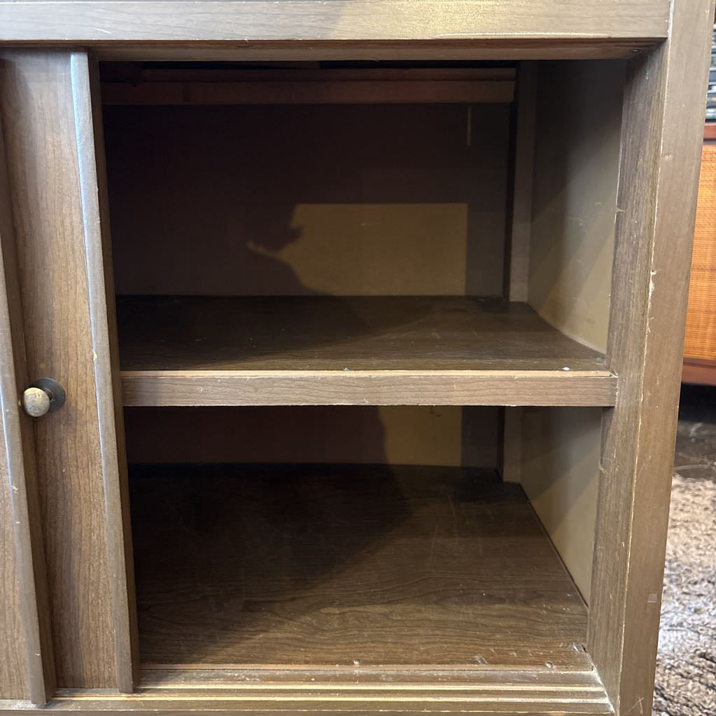 A large wooden hutch with two sliding wooden doors. The cabinet is in a store setting.