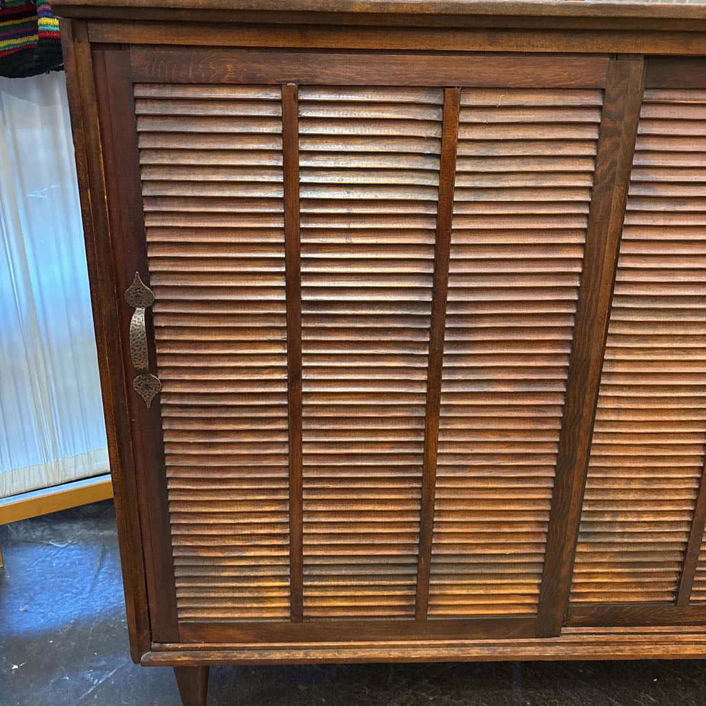 A brown wooden cabinet with sliding doors in a room setting.