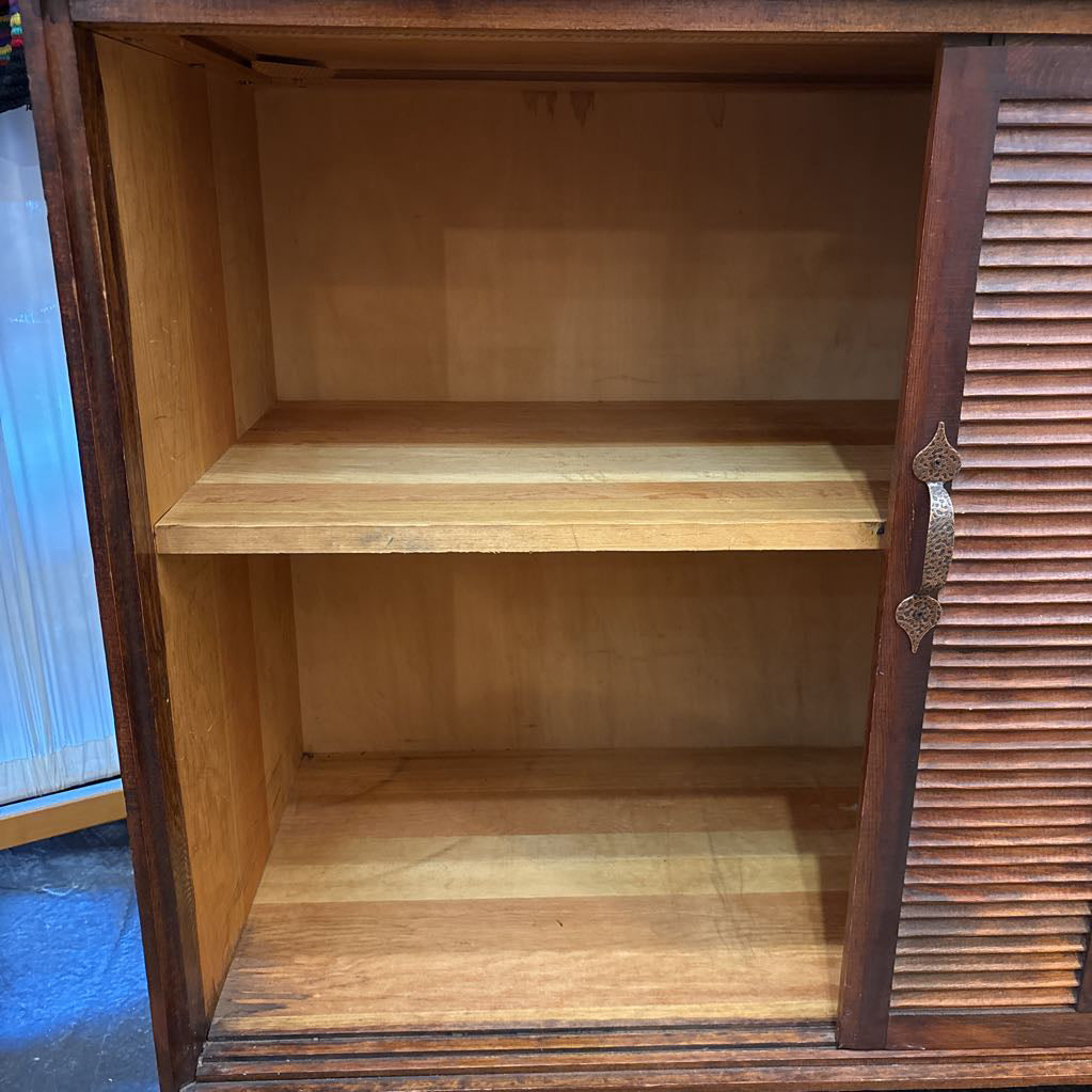 A brown wooden cabinet with sliding doors in a room setting.