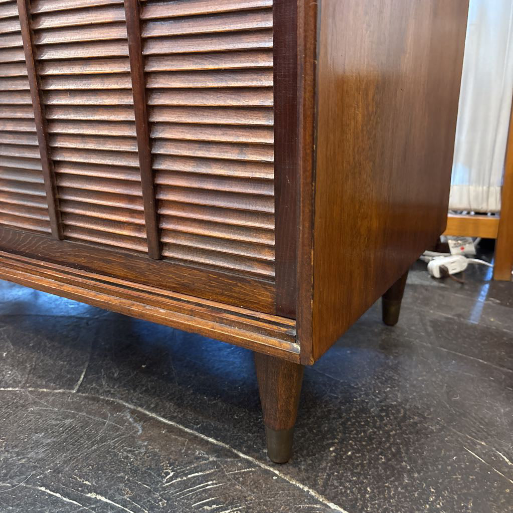 A brown wooden cabinet with sliding doors in a room setting.