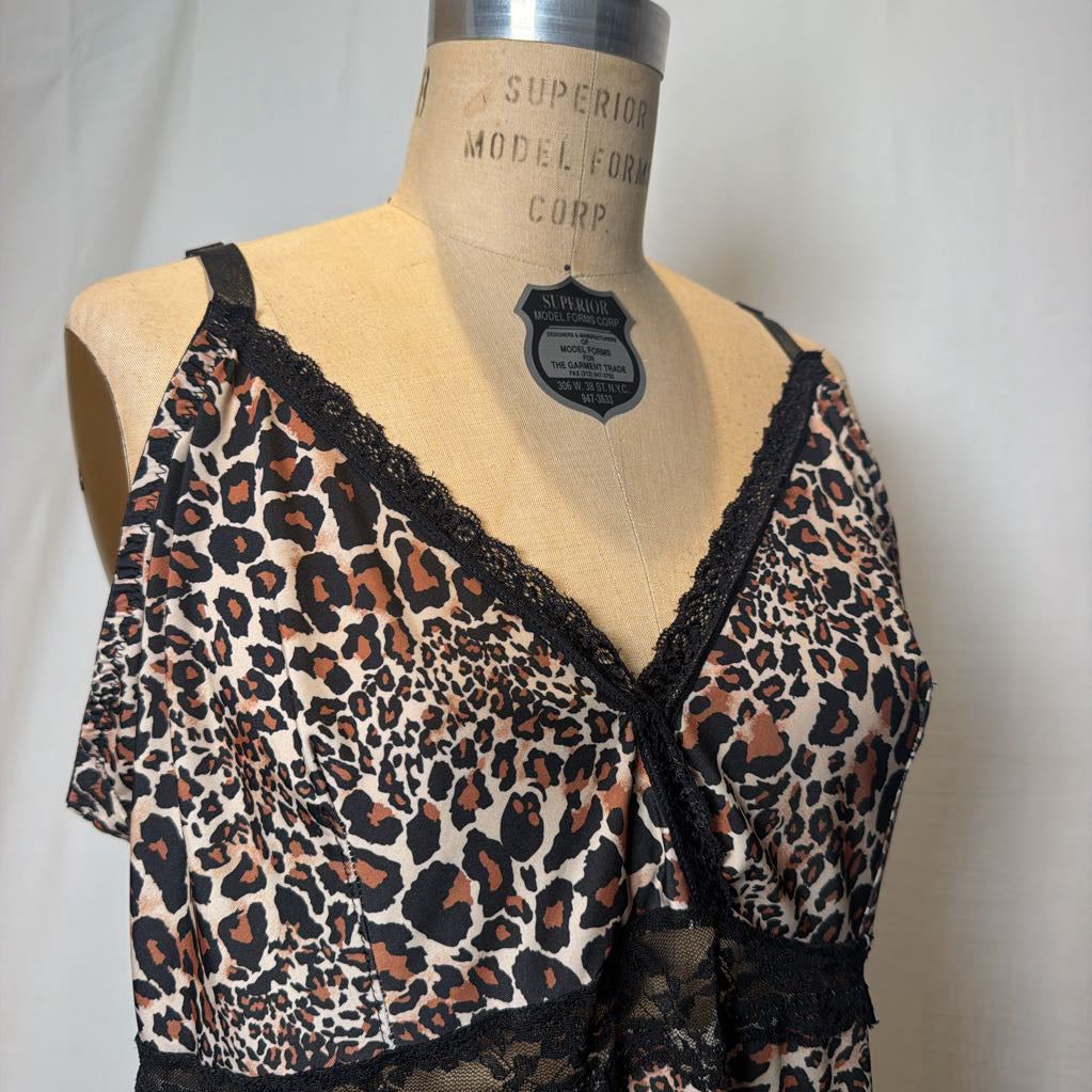 A leopard print lingerie slip dress with black lace trimmings on an antique style mannequin in front of a white fabric wall.
