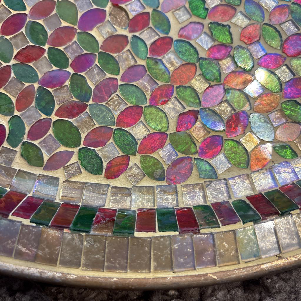 A large tray with a glass mosaic design on a brown rug.