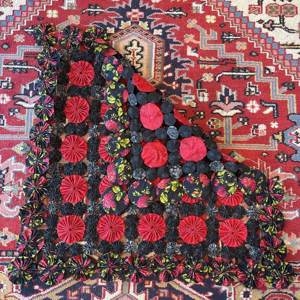 A red and black puff quilt on a red rug.