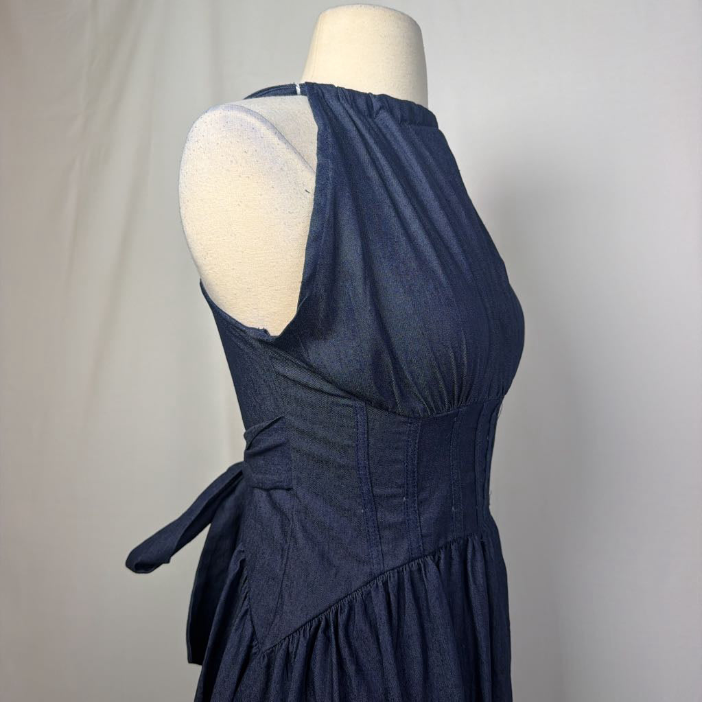A dark indigo blue halter dress displayed on a cream mannequin torso against a light gray fabric backdrop.