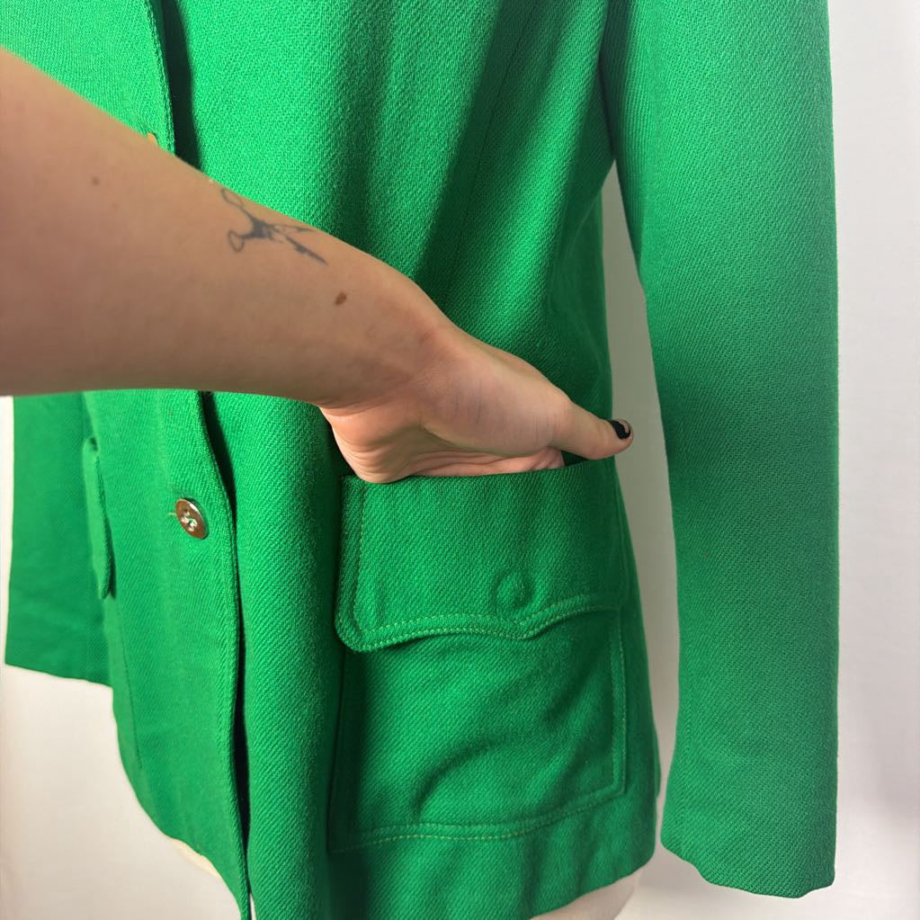 A close-up of a bright green textured jacket or cardigan with three brown buttons, shown on a white mannequin torso against a white background.